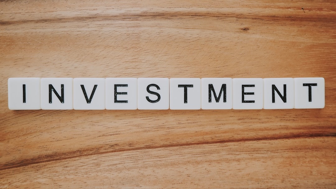 Property Investments White letter tiles spelling out the word "INVESTMENT" are arranged in a straight line on a wooden surface, symbolizing financial growth and wealth-building.