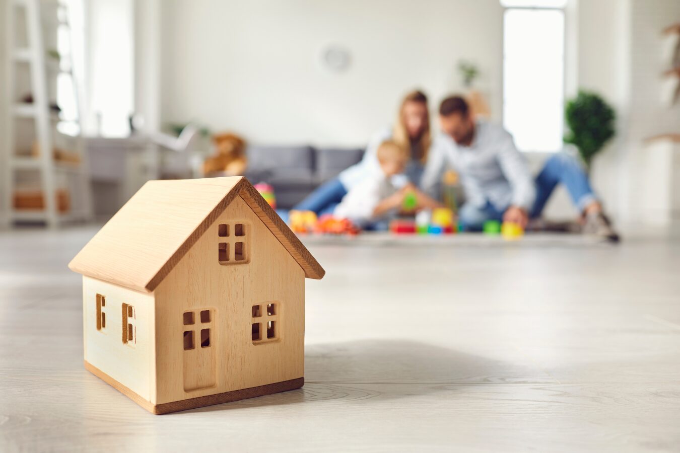a wooden house on a floor with a family in the background